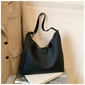 Detailansicht der schwarzen Hobo-Tasche aus Leder mit Narbung auf einem silbernen Koffer