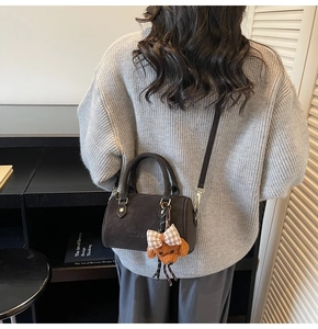 Detail of dark brown suede Boston bag featuring MDoll logo and a cute teddy bear charm