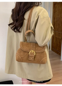 Close-up of retro brown crossbody bag with large gold buckle and white stitching detail