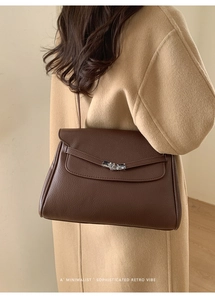 Detail of dark brown pebble leather tote bag with silver twist lock on camel wool coat