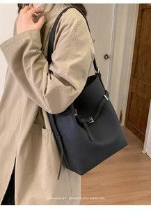 Detail der schwarzen Shopper-Tasche aus genarbtem Leder mit silberner Schnalle am Mantel