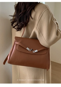 Detail view of brown pebbled leather tote bag showing retro minimalist texture and buckles