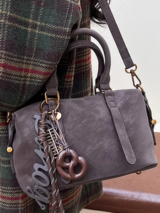 Grey suede Boston bag with charms worn over a plaid coat for an autumn fashion look
