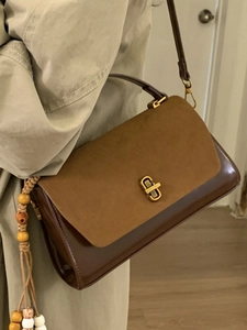Vintage brown leather shoulder bag with suede flap, gold swivel lock, and beaded charm