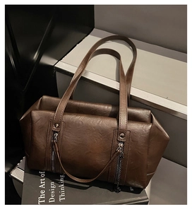 Detailed macro view of deep brown leather tote bag featuring vertical zippers and chain charms