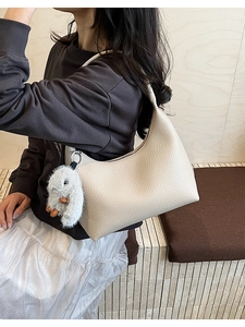 Close-up of beige lychee grain leather hobo bag with cute plush bunny pendant accessory