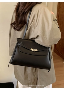 Detail of minimalist black leather tote bag with silver rotary lock and pebble grain texture