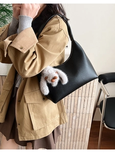 Model wearing black pebble leather crescent bag with cute white plush bunny charm