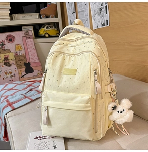 Détail du sac à dos jaune clair à motif d'étoiles avec un pendentif lapin en peluche