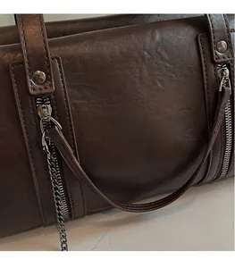 Detailed macro view of dark brown leather handbag with vertical zippers and metal chain