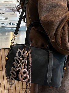 Chic black Boston handbag for women featuring creative charms and golden hardware details