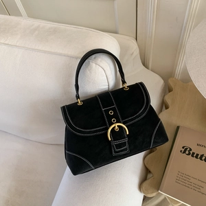 Detail of black suede handbag with white stitching and oversized gold circular buckle
