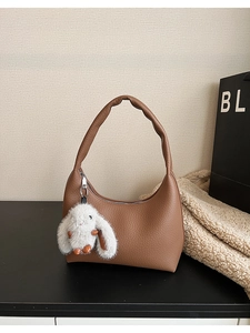 Detail view of brown pebbled leather hobo bag with a white plush rabbit charm accessory