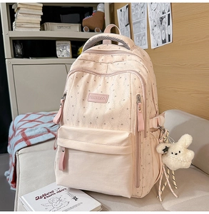 Sac à dos rose étoilé avec pendentif lapin mignon posé sur un canapé doux