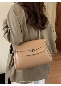 Close-up of a beige lychee leather tote bag featuring a silver metal twist lock closure