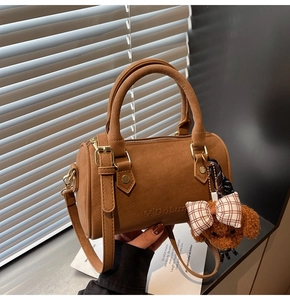 Close-up of caramel Boston bag with MiDoLun logo, dual handles, and plush dog charm