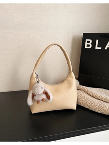 Detail of beige crescent shoulder bag with lychee texture and plush rabbit pendant