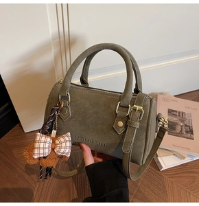 Detail view of olive green Boston bag with leather texture and cute dog charm pendant