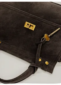 Close-up of vintage brown leather handbag featuring a glossy gold clasp and key charm