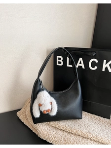 Detail of black lychee grain crescent bag with a white rabbit fur charm attachment