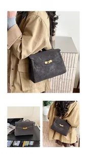 Detail of a charcoal gray textured shoulder bag with a gold metal lock and gusseted sides