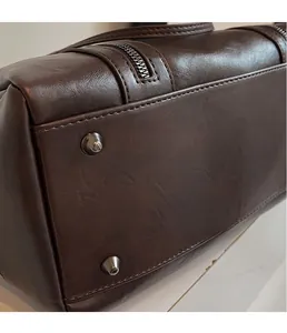 Detailed close-up of dark brown leather handbag with silver metal cone rivets and neat stitching