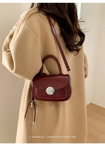 Detailed view of the vintage wine red leather saddle bag worn with a beige wool coat