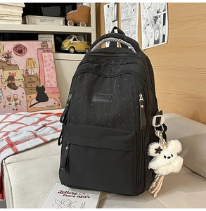 Détail du sac à dos noir à motif étoilé avec pendentif ours et grande contenance