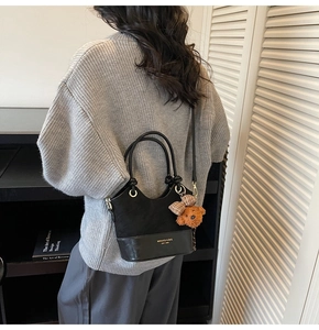 Detail of black crossbody bag with textured leather, logo print, and bear charm