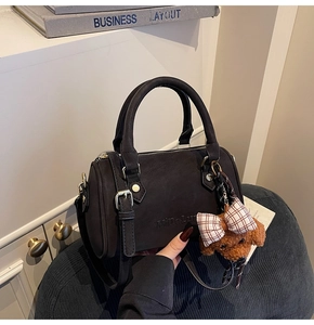 Detail of black Boston handbag with embossed logo and brown teddy bear charm accessory