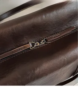 Detailed macro view of the dark brown leather bag showing dual zippers and long pullers