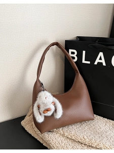 Detailed close-up of a brown textured leather hobo bag featuring a white rabbit plush charm