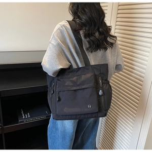 Detailansicht der schwarzen Nylon-Einkaufstasche mit Taschen und metallischem CM-Logo