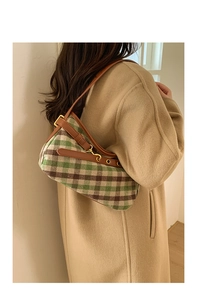 Modella indossa una borsa sottobraccio vintage a quadri verde e marrone in pelle