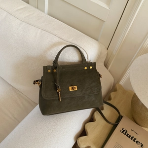Detailed macro view of olive suede handbag with gold lock and decorative key pendant