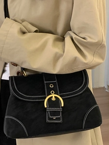 Retro black leather handbag with white stitching and gold ring buckle shown with trench coat