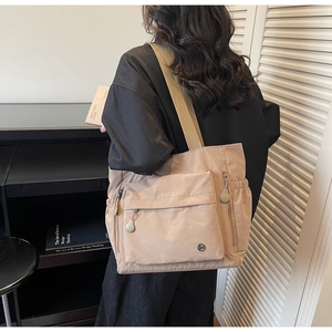 Detailansicht der khakifarbenen Nylon-Tragetasche mit Multi-Pocket-Design und Metall-Logo