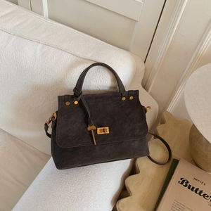 Detail of dark grey suede handbag featuring gold metal lock and unique key charm detail