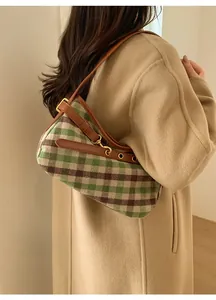 Dettaglio della borsa baguette a scacchi con tracolla in pelle indossata su un cappotto beige