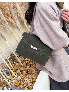 Deep olive green vintage leather tote bag with gold hardware shown in an autumn setting