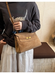 Detail of vintage brown leather tote bag with gold metal buckle and matte texture