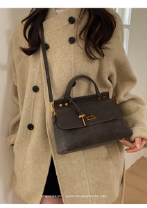 Detail of dark grey retro handbag with gold rotating lock and key charm decoration
