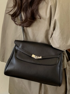 Classic black leather tote bag with silver hardware on model in beige trench coat