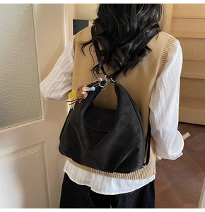 Detail of a large black vintage tote bag with cute charms worn as a shoulder bag