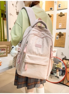 Détail d'un sac à dos rose avec imprimés étoiles, grand compartiment et pendentif peluche