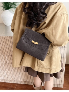 Detail view of deep brown tote bag with gold metal clasp on model for daily commuting