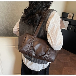 Detail of dark brown retro shoulder bag with smooth leather texture and metal chain