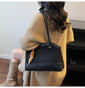 Detail of black suede patchwork shoulder bag with colorful wooden beads and brand logo