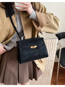 Detailed close-up of a black vintage crossbody bag with a gold buckle and textured leather