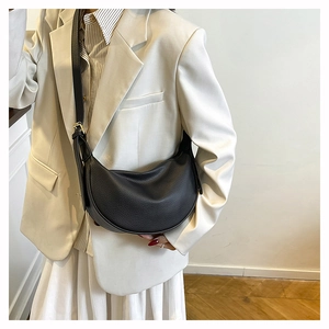 Close-up of black crescent crossbody bag in soft litchi grain leather on a model